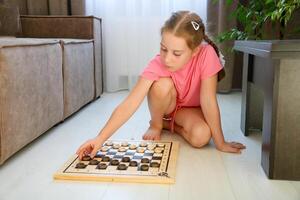pequeño niña colocación juego de damas en un tablero de ajedrez para un juego foto