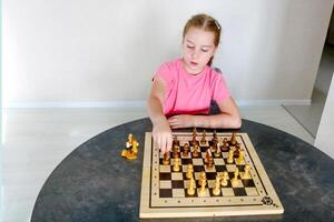 pequeño niña a el mesa jugando ajedrez foto