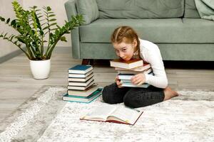 little girl trying to hold a stack of books photo