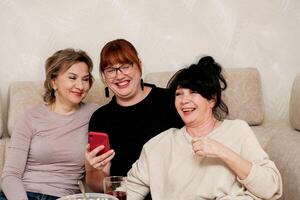 three laughing women taking a selfie photo