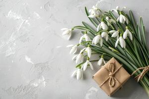 AI generated A bouquet of snowdrops and a gift box on an empty gray background with copy space. Spring composition photo