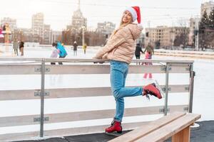 Beautiful lovely middle-aged girl blonde hair warm winter jackets knitted glove stands ice rink background Town Square. Christmas mood lifestyle photo