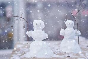 dos pequeño linda muñecos de nieve con ramas en lugar de manos foto