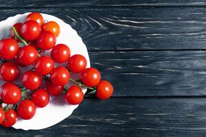 Cereza Tomates en el blanco plato en el de madera mesa foto