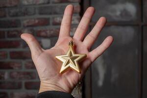 Golden five pointed star decoration in hands on black background. photo