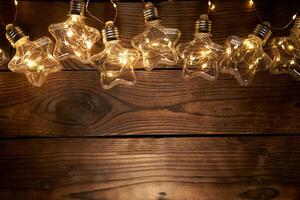 Bright luminous Christmas garlands in the shape of stars lie on a dark wooden background. photo
