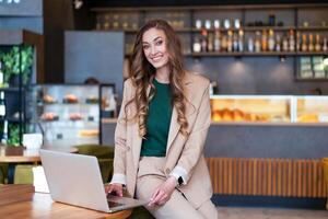 negocio mujer restaurante propietario utilizar ordenador portátil en manos vestido elegante traje pantalón sentado en mesa en restaurante con bar mostrador antecedentes foto