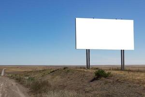 Blank billboard on the road in the steppe with blue sky photo