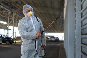 trabajador vistiendo protector traje desinfección engranaje desinfectar superficie público sitio foto