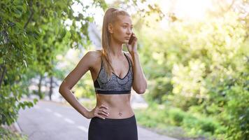 Woman runner standing before exercising summer park Talking on the phone. photo