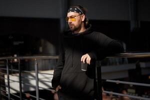 Handsome young unshaven man black hoodie and bandana stands photo