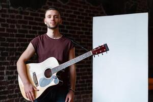 Man with acoustic guitar standing near whiteboard Music school concept photo