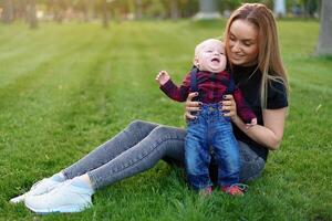 Beautiful young mother walks with her little son in a summer park photo