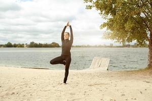 fitness, sport, people and lifestyle concept - young woman making yoga exercises on beach photo