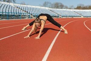 young fitness woman runner warm up before running on track photo