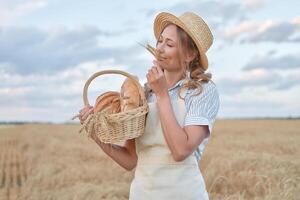 Female farmer standing wheat agricultural field Woman baker holding wicker basket bread product photo