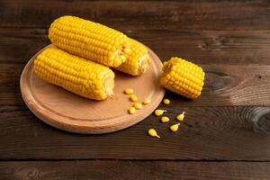 Corn cob with lies on cutting board wooden table background. photo