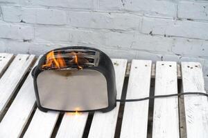 Burning toaster. Toaster with two slices of toast caught on fire over white background photo