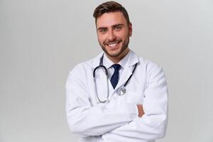 Young handsome modern doctor in a white medical gown stands in the studio on a white background. Student trainee of a medical university. photo