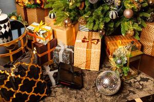 Close up of decorated Christmas tree with lots of gifts of golden, brown and black colors and large silver disco balls photo