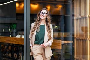 negocio mujer restaurante propietario vestido elegante traje pantalón en pie cerca restaurante grande ventana foto