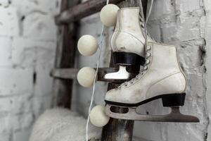 A pair of white leather sports skates hang on a cord on the wall. Good New Year spirit. Beautiful calm background photo