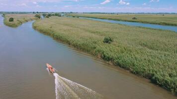 A boat with tourists rushes quickly along the river. Elderly tourism. Tourists in life jackets. Aerial view. Video from drone.