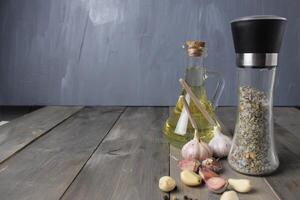 Garlic cloves and vegetable oil in a bottle on a gray background with space for text. Preparation of aromatic oil photo
