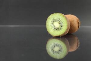 Whole and half fruit kiwi berries lie on a black background with a copyspace photo