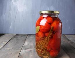 Enlatado alimento. salado Tomates en un vaso tarro en un gris antecedentes con espacio para Copiar espacio texto. hecho en casa preparativos foto