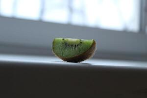 cuña rebanada de kiwi en un ventana umbral blanco ligero antecedentes con un copyspace foto