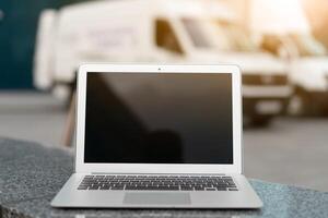 Open Laptop Black Screen With Office Building And Truck On Background photo