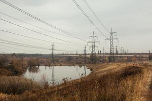 Coal power station in beautiful area full of trees and lake, mirror reflection of energetic pole and power station with chimneys, synergy of industry and nature photo