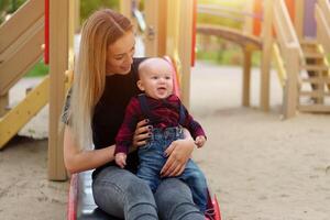 hermosa joven madre camina con su pequeño hijo en un verano parque foto