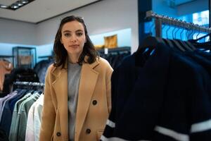 Woman choose what to buy in clothes store photo