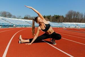 young fitness woman runner warm up before running on track. Morning exercises at summer photo