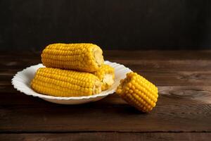 Corn cob lies on white plate wooden table background. photo