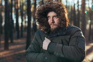 close up portrait of a bearded hipster tourist in gray hood man in the sunlight photo