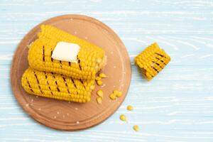 Grilled hot Corn cob lies on cutting board blue wooden table background. photo