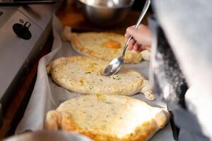 Culinary master class. Closeup of people hands preparing khachapuri. Traditional georgian cheese bread. Georgian food photo