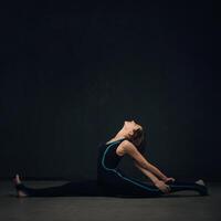 mujer practicando yoga en contra un oscuro texturizado pared foto