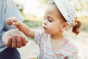 A little girl pours sand into her unrecognizable fathers hand. The concept of the transience of time and the fact that new generations replace the old photo