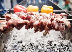 Grilled kebab cooking on metal skewer. Roasted meat cooked at barbecue. with Red and yellow Bell pepper photo