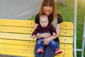 hermosa joven madre camina con su pequeño hijo en un verano parque foto