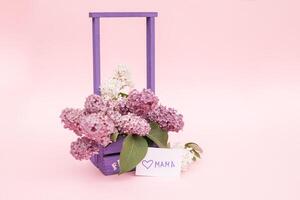 Beautiful bouquet of purple lilac and card on purple paper background photo