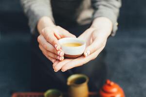 Woman offers hot tea in a vintage ceramic cup. photo