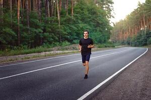 caucásico medio años hombre atleta carreras soleado verano día en asfalto la carretera en el bosque. foto