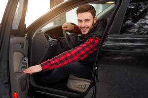 Young attractive Caucasian man sits at the wheel of his car sunny winter day. photo