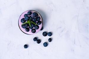 Tasty fresh blueberry yoghurt shake dessert in ceramic bowl standing on white table background. photo