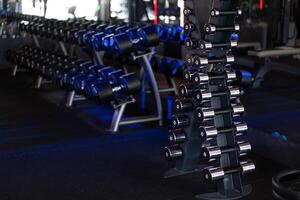 Dumbbells in a row at gym Dark toned photo